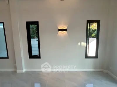 Modern minimalist interior with sleek wall lighting and large windows, perfect for natural light lovers.