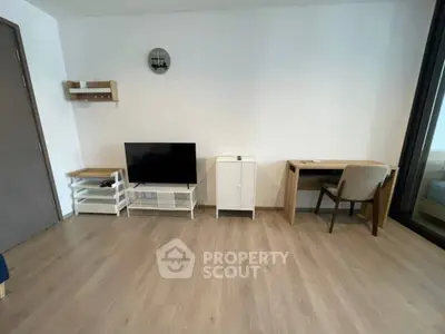 Modern minimalist living room with TV, desk, and wooden flooring.
