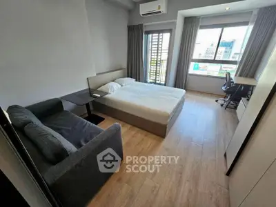 Modern bedroom with large window and city view, featuring a cozy bed and stylish furniture.