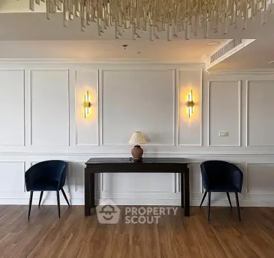 Elegant living room with modern lighting and stylish furniture, featuring a chic console table and plush chairs.
