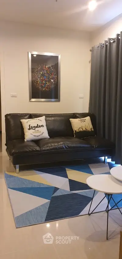 Chic modern living room with sleek black leather sofa, vibrant geometric rug, and abstract wall art creating a stylish urban living space.