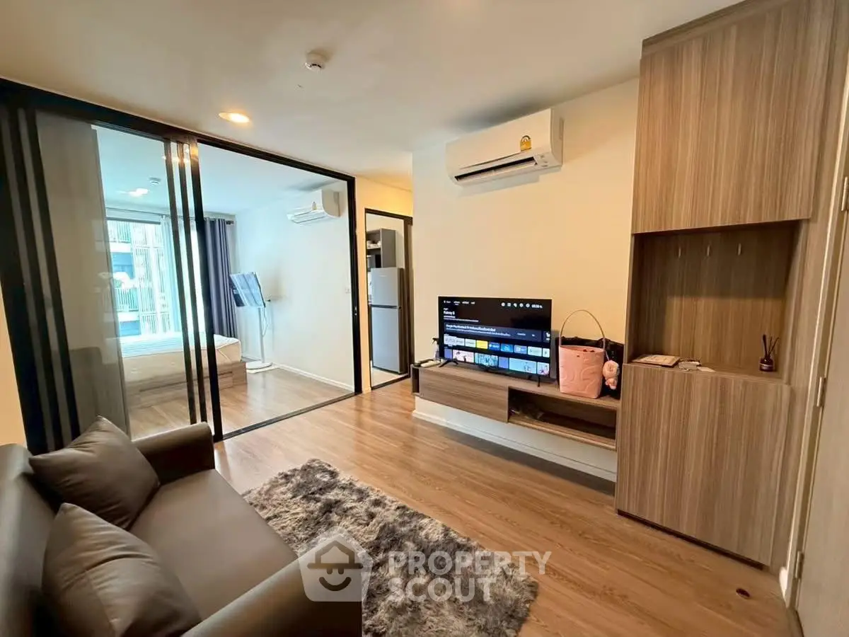 Modern living room with sleek design, featuring a cozy sofa, flat-screen TV, and stylish wooden flooring.