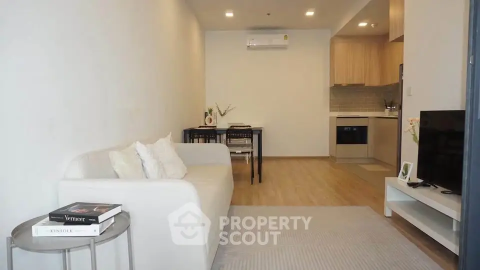 Modern living room with cozy sofa and open kitchen layout in stylish apartment.