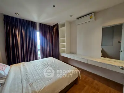 Cozy bedroom with natural light, featuring a comfortable bed, built-in shelves, and air conditioning.