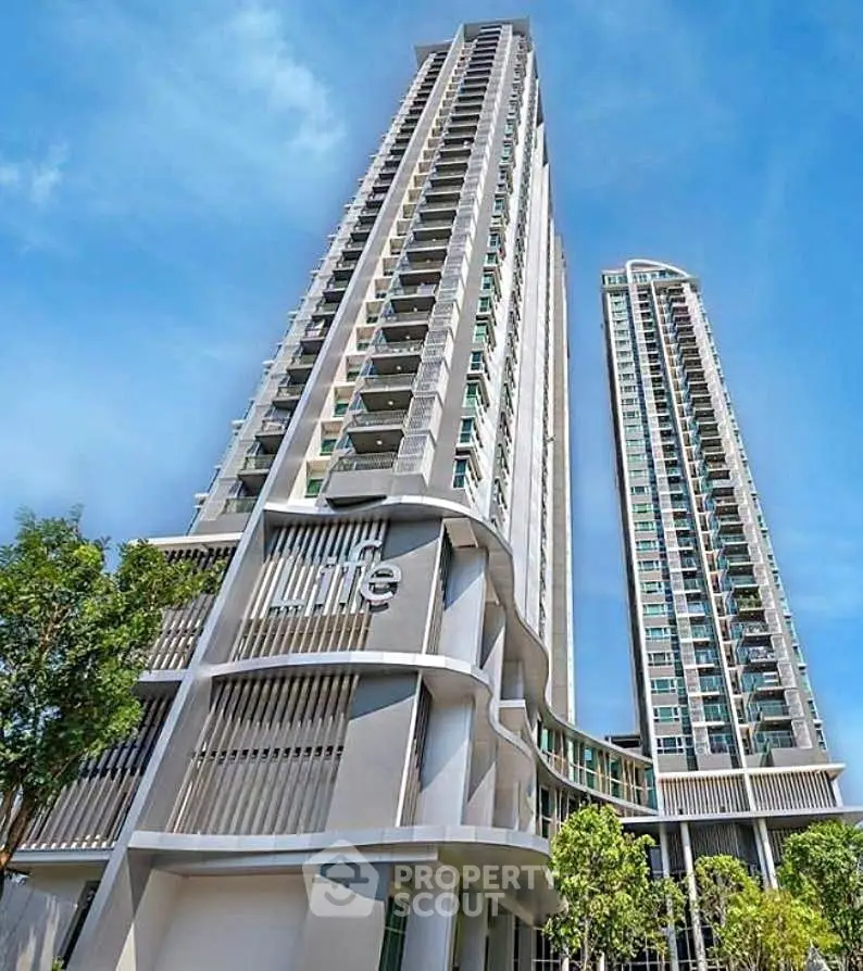 Stunning modern high-rise residential building with sleek architectural design and lush surroundings.
