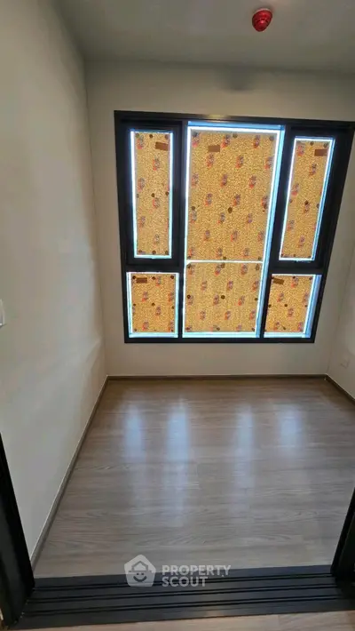 Spacious empty room with large windows and wooden flooring, perfect for customization.