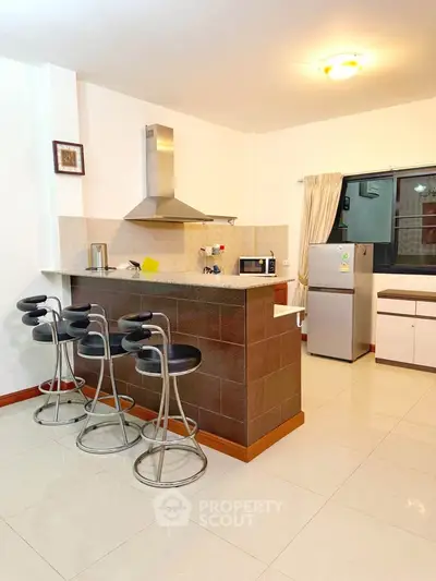 Modern kitchen with breakfast bar and stainless steel appliances in a bright, open layout.