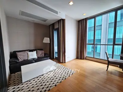 Modern living room with large windows, wooden flooring, and stylish furniture in a high-rise apartment.