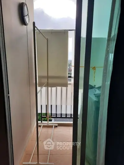 Cozy balcony with sliding glass door and clothes drying rack, perfect for urban living.