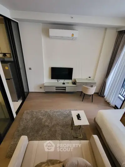 Modern living room with sleek furniture and air conditioning, featuring a cozy seating area and a flat-screen TV.