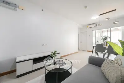 Modern living room with sleek furniture and open kitchen layout in a bright apartment.
