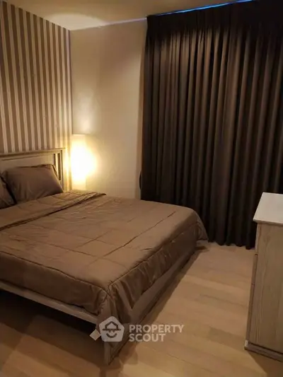 Cozy bedroom with elegant striped wallpaper and warm lighting, perfect for relaxation.