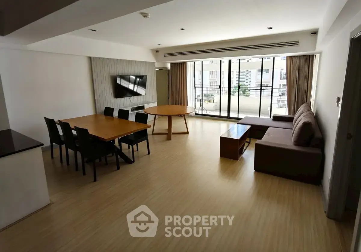 Spacious modern living room with dining area and large windows leading to balcony.