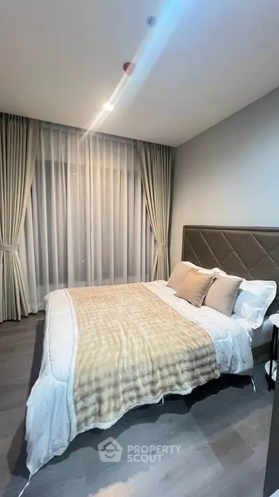 Modern bedroom with elegant decor and large window draped with curtains, creating a cozy and inviting atmosphere.
