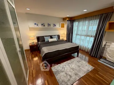 Elegant bedroom with wooden flooring and large windows for natural light.