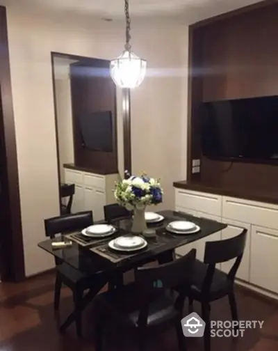 Elegant dining area with modern glass table and stylish decor in a cozy apartment setting.