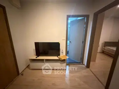 Cozy apartment interior with TV stand and open door to bedroom, showcasing modern living space.