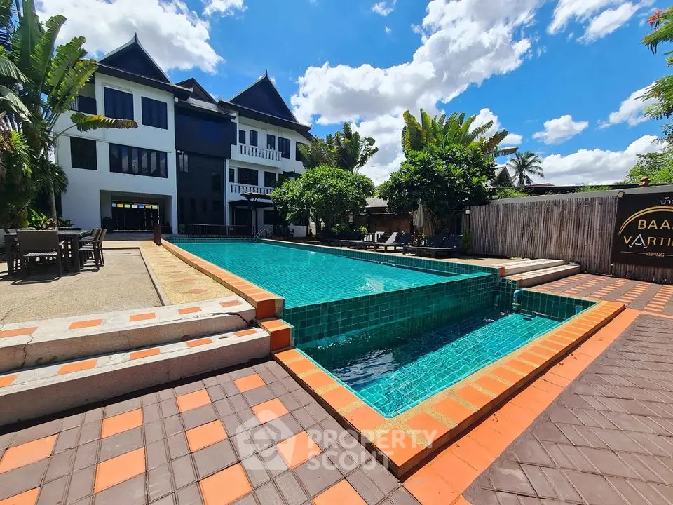 Stunning poolside view of modern villa with lush greenery and clear blue skies.