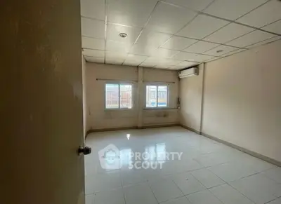 Spacious empty room with tiled floor and large windows, ideal for customization.