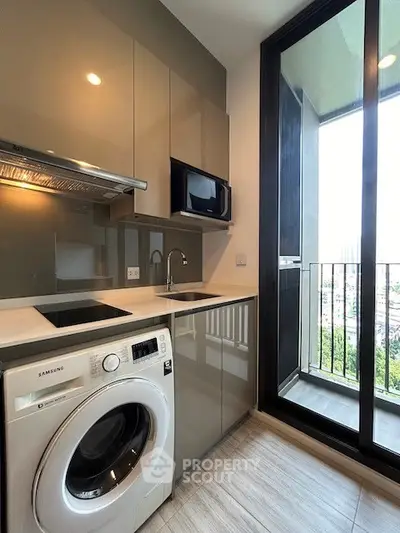 Modern kitchen with sleek cabinetry, washing machine, and balcony view in a high-rise apartment.
