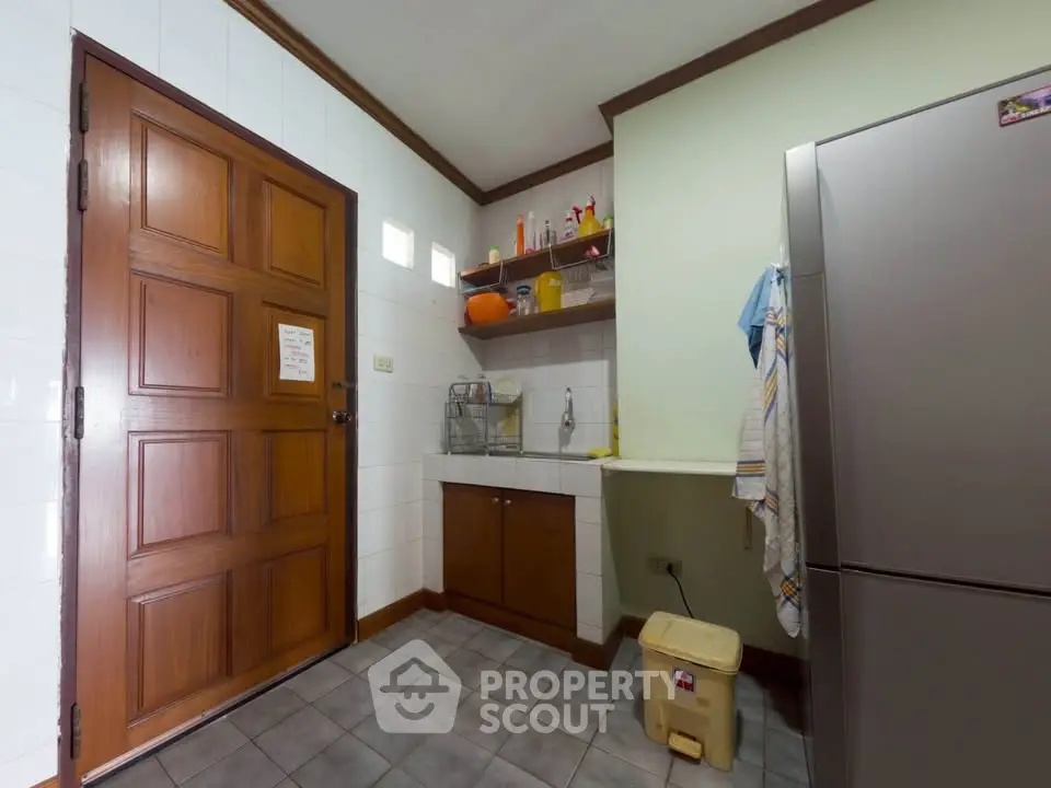 Charming kitchen with wooden door and stainless steel fridge, perfect for cozy home cooking.