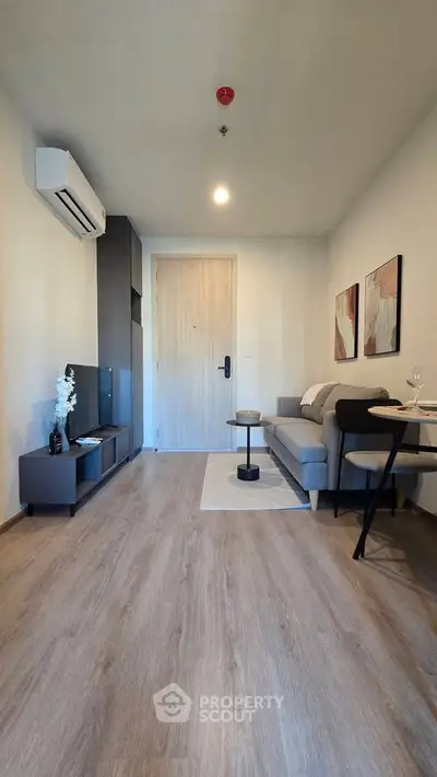Modern living room with sleek furniture and wooden flooring, featuring a cozy sofa and stylish decor.
