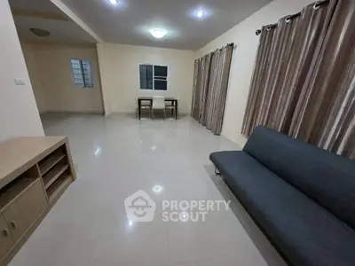 Spacious living room with modern furnishings and elegant curtains, perfect for comfortable living.