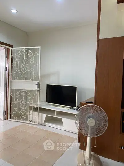 Cozy living room with TV and fan, featuring elegant white door and tiled flooring.