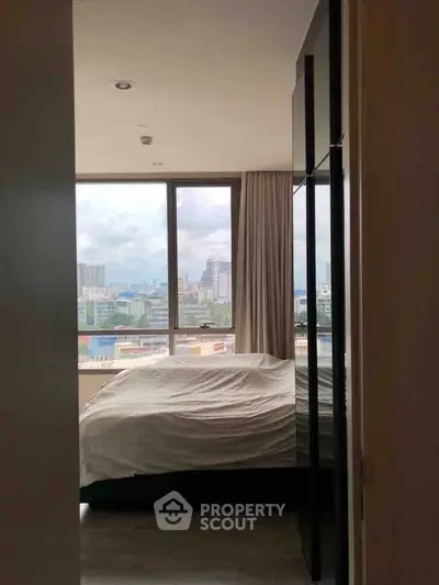 Modern bedroom with large window offering stunning city views, perfect for urban living.