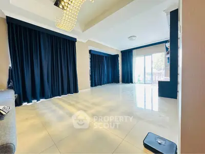Spacious living room with elegant chandelier and large windows for natural light.