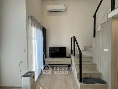 Modern living room with staircase, TV, and air conditioning in stylish apartment