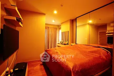 Cozy bedroom with warm lighting, mirrored wardrobe, and modern decor for a relaxing ambiance.