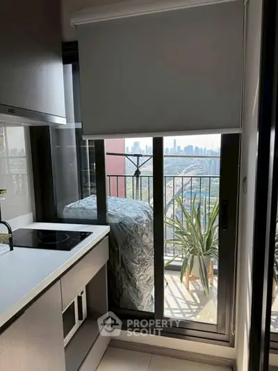 Modern kitchen with balcony view of city skyline, featuring sleek appliances and natural light.