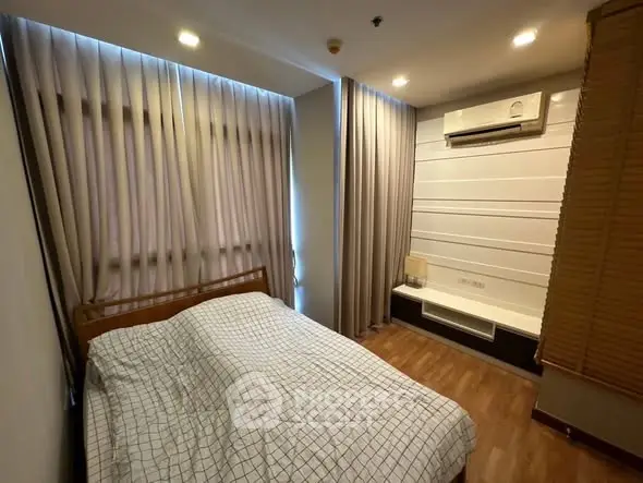 Cozy bedroom with modern decor and air conditioning, featuring elegant curtains and wooden flooring.