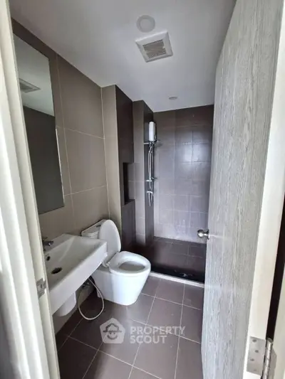 Modern bathroom with sleek design featuring a shower, toilet, and sink in neutral tones.