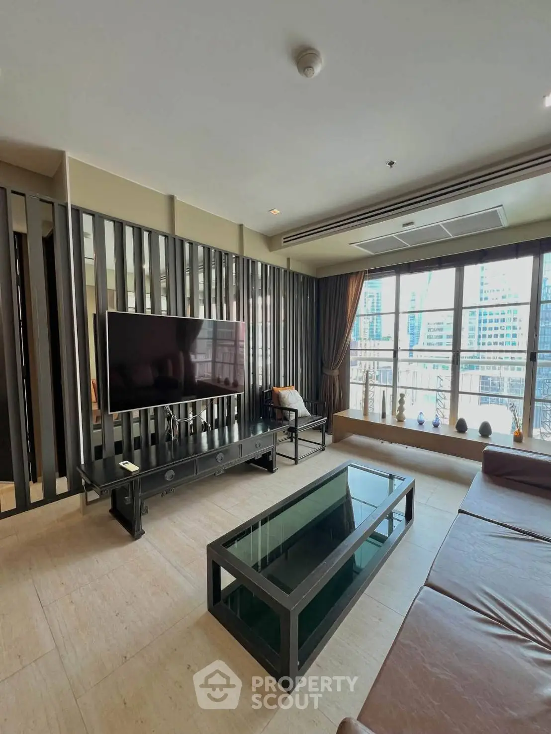 Spacious modern living room with large windows and city view, featuring sleek furniture and contemporary design.