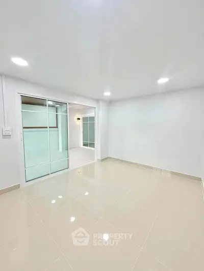 Spacious modern living room with sleek tile flooring and sliding glass doors.