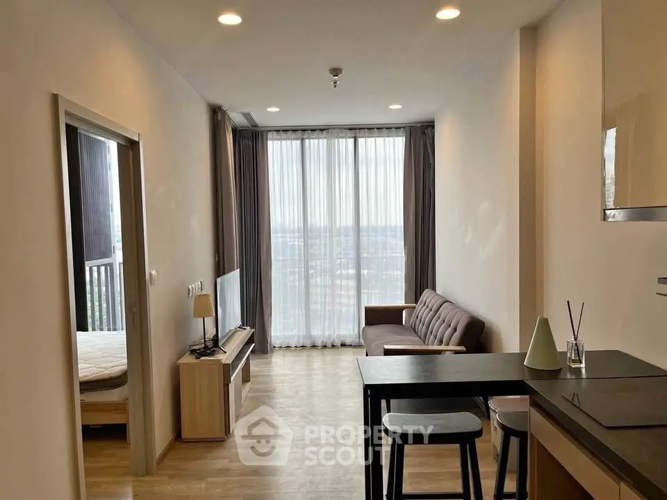 Modern apartment interior with open layout, featuring a cozy living area and large windows with a view.
