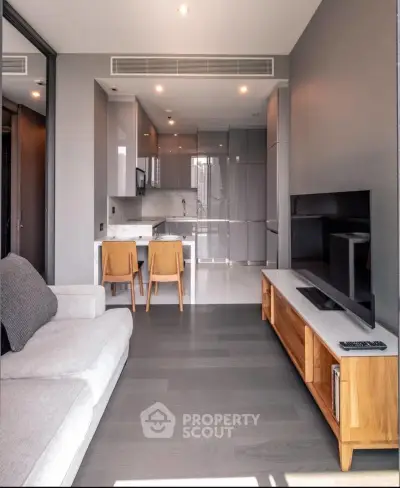 Modern living room with sleek kitchen, open layout, and stylish furniture in a contemporary apartment.