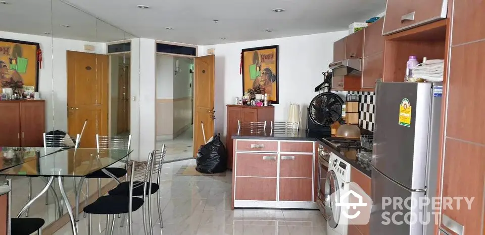 Modern kitchen with glass dining table and stainless steel appliances in stylish apartment.