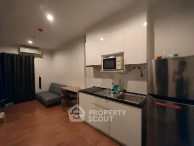 Modern compact kitchen with microwave and fridge in cozy apartment