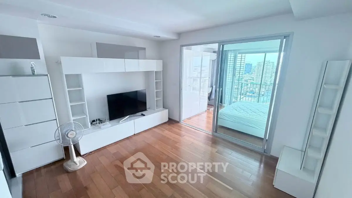 Modern living room with sleek furniture and city view, featuring hardwood floors and sliding glass doors.