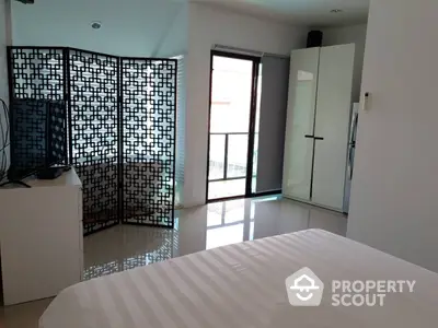 Spacious bedroom with glossy tiled flooring, modern privacy screen, and ample natural light from balcony access.