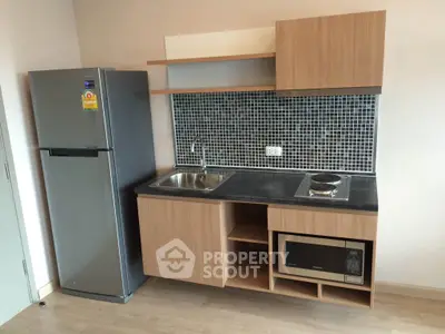 Modern compact kitchen with sleek appliances and stylish backsplash in a cozy apartment.