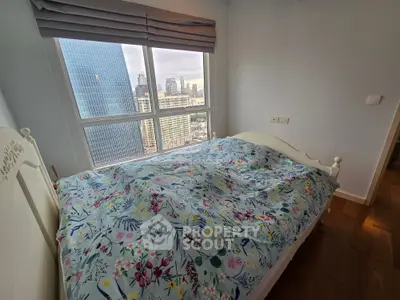 Cozy bedroom with city view, featuring floral bedding and large window for natural light.
