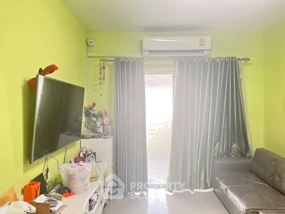 Cozy living room with bright green walls, modern sofa, and wall-mounted TV, perfect for relaxation.