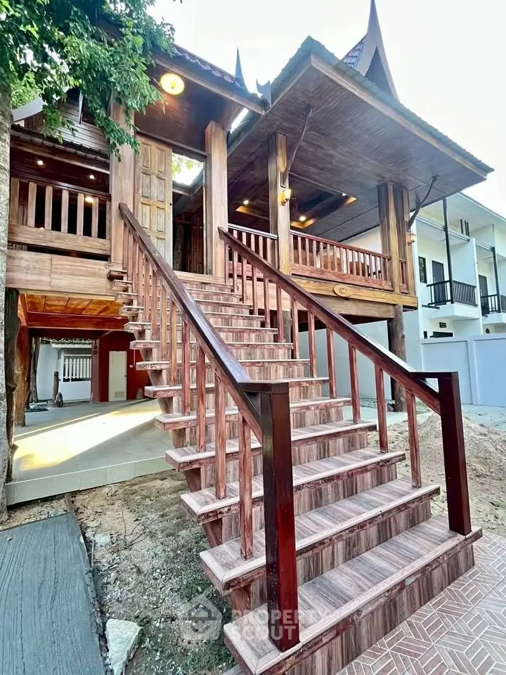 Charming traditional wooden house with elevated entrance and intricate staircase design.