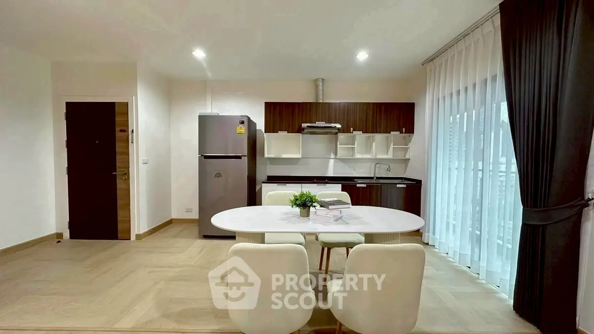 Modern open-layout kitchen with dining area, featuring sleek cabinetry and natural light.