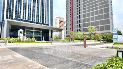 Modern high-rise building entrance with sleek design and lush landscaping.