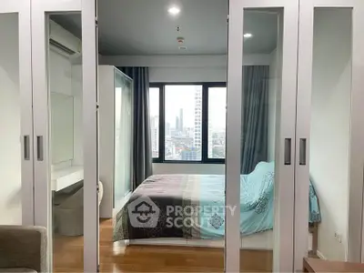 Modern bedroom with mirrored closets and city view, featuring stylish decor and ample natural light.
